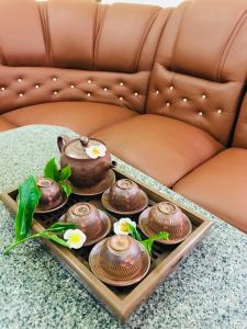 a tray with tea pots and flowers on a couch at Bao Loc Homestay in Bao Loc