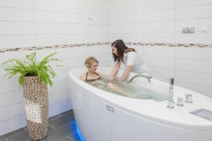kobieta w wannie z dziewczyną w obiekcie Főnix Wellness Resort w mieście Csitár