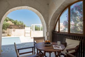 un patio con mesa, sillas y piscina en Athena Villas en Makry Gialos
