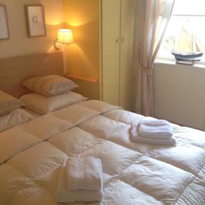a white bed with towels on it with a window at bord de mer in Sint-Idesbald