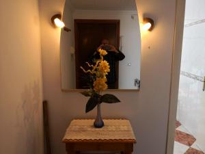 a person taking a picture of a vase of flowers in a mirror at Piso Vacacional Isla Cristina in Isla Cristina