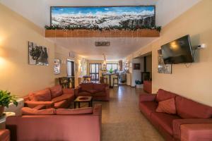 a living room with couches and a flat screen tv at Hotel Faggio Rosso in Pescasseroli