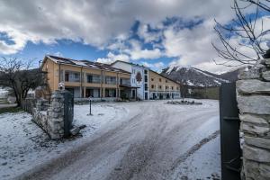 a building on a snow covered road with mountains in the background at Hotel Faggio Rosso in Pescasseroli