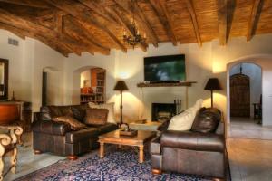 a living room with two leather couches and a tv at Villa Thornhill in Palm Springs