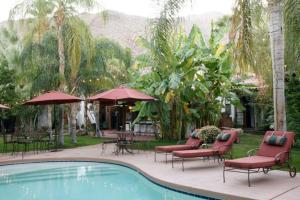 a resort pool with chairs and tables and umbrellas at Villa Thornhill in Palm Springs