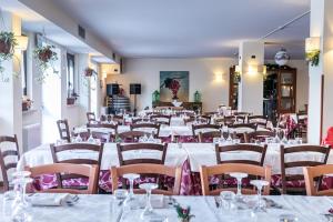 um quarto com mesas brancas e cadeiras com guardanapos cor-de-rosa em Hotel Faggio Rosso em Pescasseroli