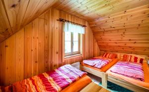 two beds in a log cabin with a window at Chalupa Pod lomem - Malá in Dolní Morava