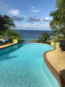 a swimming pool with the ocean in the background at Alexanders Penthouse on the beach in Ocho Rios