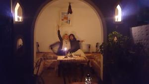 twee mensen zitten op een tafel in een woonkamer bij Dar naya in Chefchaouene