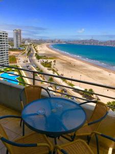 een tafel en stoelen op een balkon met uitzicht op het strand bij Condominio Costa Peñuelas in Coquimbo