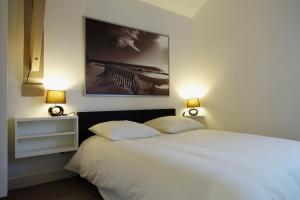 um quarto com uma cama branca e 2 almofadas em Gite "Avoine" em Falaise