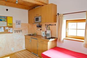 una piccola cucina con letto rosso in una camera di Ferienwohnung Bacher a Edling