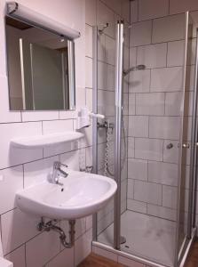a white bathroom with a sink and a shower at Ferienhaus am Silbersee Leni in Frielendorf