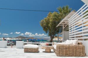 um pátio com cadeiras de vime, uma mesa e palmeiras em Ippokampos Beachfront em Naxos Chora