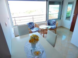 Una mesa blanca con un jarrón de flores. en Apartments Linda, en Trogir