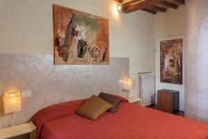 カステル・サン・ジミニャーノにあるCamera La Loggiaの赤いベッドと壁に絵画が飾られたベッドルーム1室