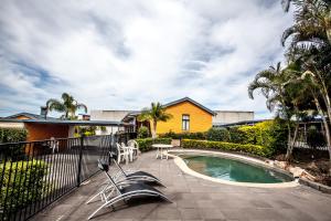 un patio trasero con piscina y una casa en Darra Motel & Conference Centre, en Brisbane