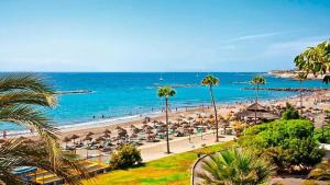 a beach with umbrellas and people on the beach at Tajinastes in Arona