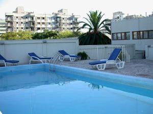 a swimming pool with blue chairs next to a building at Millenium Mendoza Apartments in Mendoza