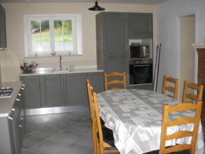 uma cozinha com uma mesa, um lavatório, uma mesa e cadeiras em Les Peupliers em Vesly
