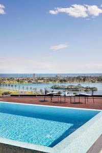 a swimming pool with chairs and a view of the water at Tyrian Albert Park Lake in Melbourne