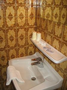 a bathroom with a sink and a shelf on a wall at Pension Auf der Olk mit Röpertsmühle in Veldenz