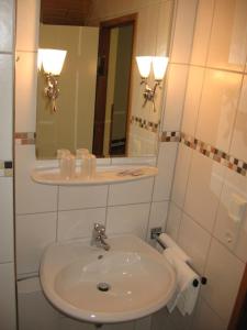 a white bathroom with a sink and a mirror at Pension Auf der Olk mit Röpertsmühle in Veldenz