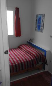 a bedroom with a bed with a red and white striped blanket at Pilar Ruiz in Asilah