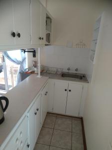 a kitchen with white cabinets and a sink at Chanelle Self Catering in Bloemfontein