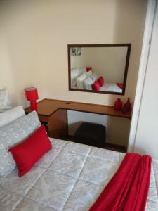 Schlafzimmer mit einem Bett und einem Schreibtisch mit einem Spiegel in der Unterkunft Chanelle Self Catering in Bloemfontein