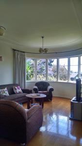 Kiwi Heritage Homestay في أوكلاند: غرفة معيشة مع كنبتين وتلفزيون