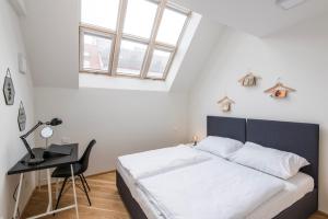 a bedroom with a bed and a desk and a window at Rehorova apartments in Prague