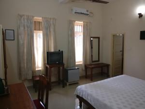 Schlafzimmer mit einem Bett, einem TV und einem Fenster in der Unterkunft Safire Residency in Thiruvananthapuram