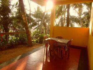 a table and chairs in a room with palm trees at Allan Guest Mirissa in Bandaramulla