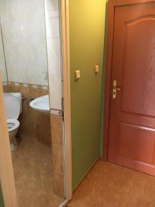 a bathroom with a toilet and a sink and a door at Arkadia Guest House in Primorsko