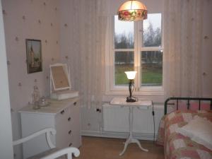 a bedroom with a bed and a dresser and a lamp at Ulrikanhovi in Loviisa