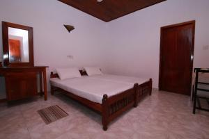 a bedroom with a bed and a table and a mirror at Budde's Beach Restaurant & Guesthouse in Hikkaduwa