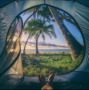 a person sitting in a tent looking out at the beach at Aotea Camp'Inn Huahine in Fare