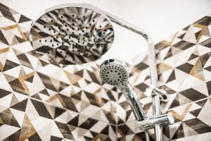 a bathroom with a shower head on a geometric wall at Apartamenty Opal in Krynica Zdrój