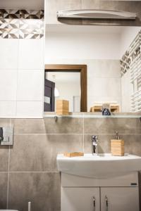 W łazience znajduje się umywalka i lustro. w obiekcie Apartamenty Opal w mieście Krynica Zdrój