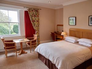 a bedroom with a bed and a desk and a window at Hundith Hill Hotel in Cockermouth