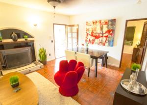 a living room with a red chair and a table at Villa Cristine - Spanish Style Palm Springs Villa in Palm Springs
