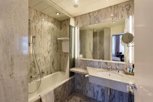 a bathroom with a tub, sink, mirror and bathtub at Glärnischhof by TRINITY in Zurich