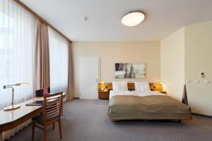 a hotel room with a bed and a desk and a bed sidx sidx at Glärnischhof by TRINITY in Zurich