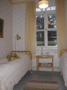 a bedroom with two beds and a table with a window at Ulrikanhovi in Loviisa