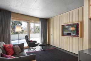 - un salon avec un canapé, une chaise et une télévision dans l'établissement Alpine Lodge Chesa a la Punt, à Pontresina