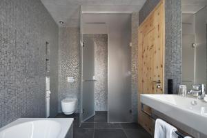 a bathroom with a sink and a tub and a toilet at Alpine Lodge Chesa a la Punt in Pontresina +26 photos