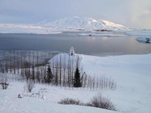 a church on an island in the water with a mountain at ION Adventure Hotel, Nesjavellir, a Member of Design Hotels in Nesjavellir
