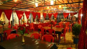 un comedor con mesas, sillas y cortinas rojas en Aziz Palace Group Of Houseboats en Srinagar