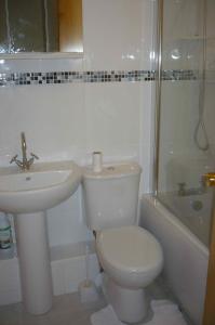 Baño blanco con aseo y lavamanos en Taverner - Self catering holiday home close to Poole Quay, en Poole